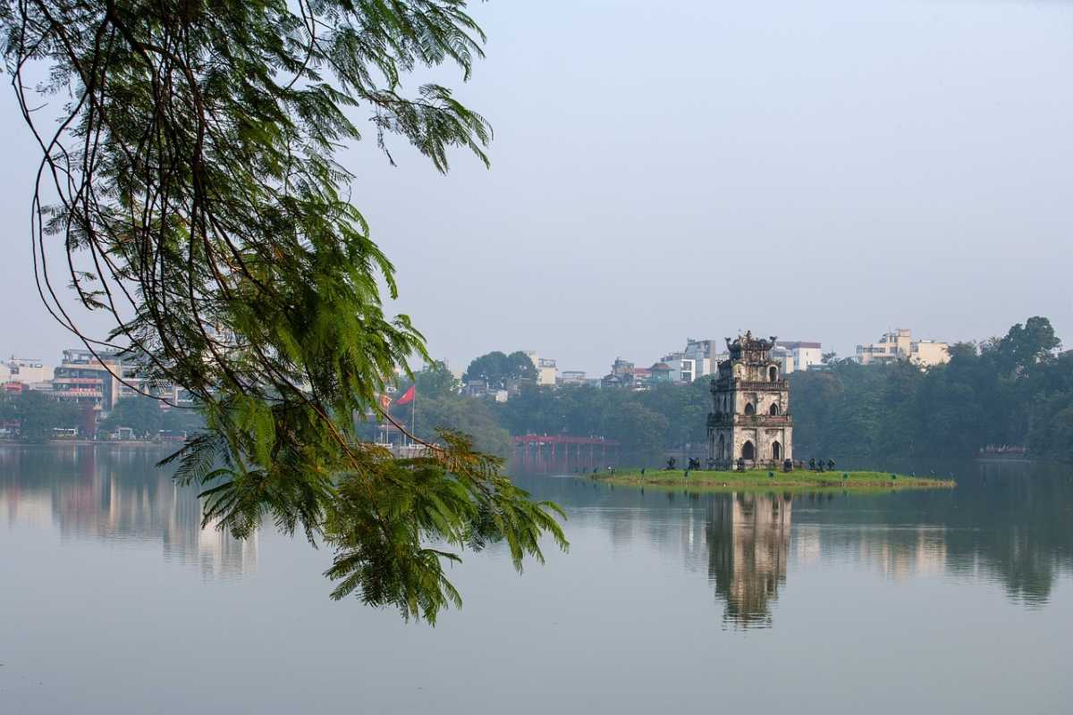Hanoi French Quarter Turtle Tower View View of Turtle Tower on Hoan Kiem Lake with trees in foreground in Hanoi French Quarter