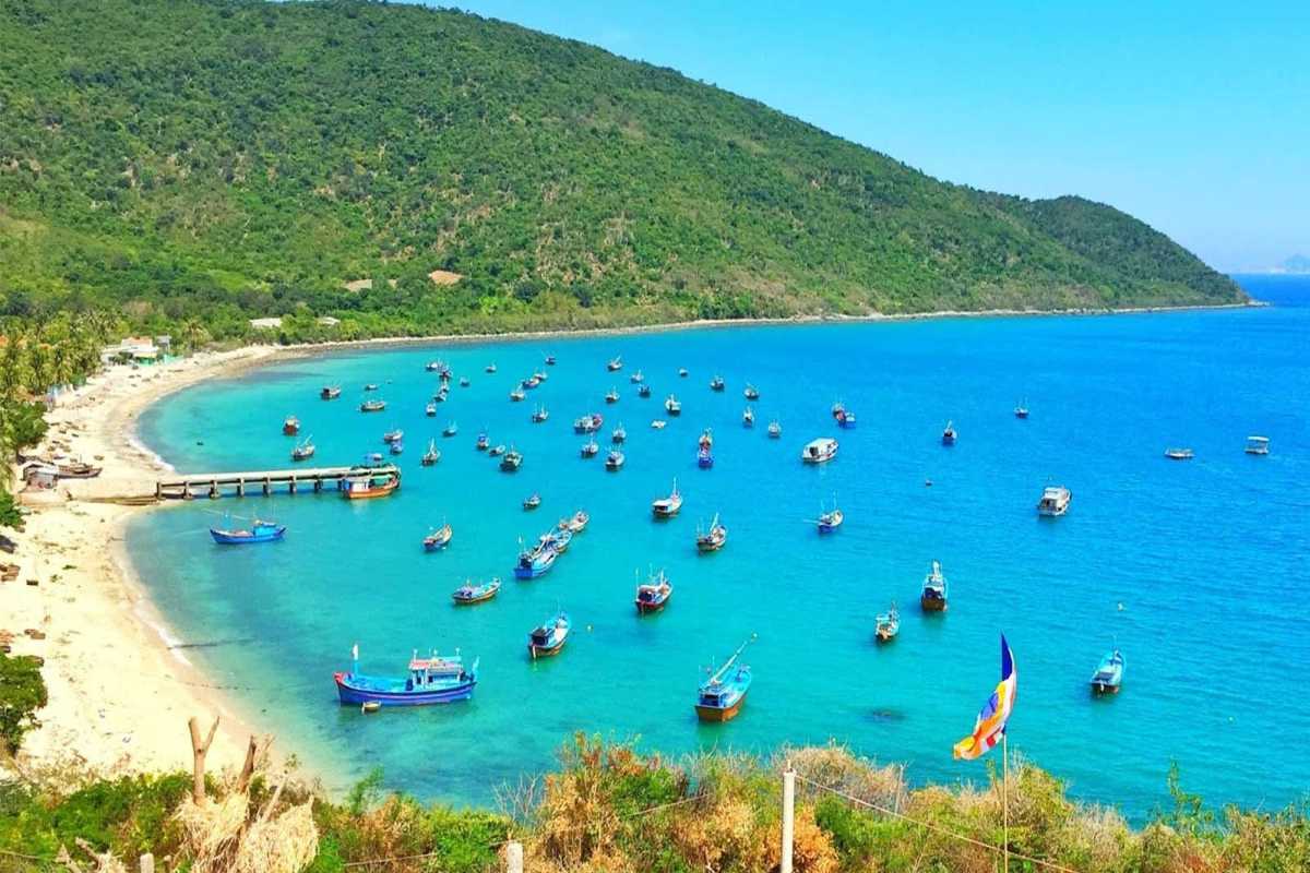 Fishing boats anchored near Van Phong Bay shoreline Traditional Vietnamese fishing boats floating on blue waters near Van Phong Bay hillside