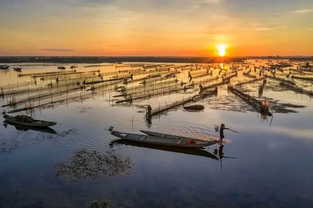 Vibrant Sunset Over Tam Giang Lagoon and Fishing Huts Colorful sunset sky over traditional fishing huts and boats on Tam Giang Lagoon