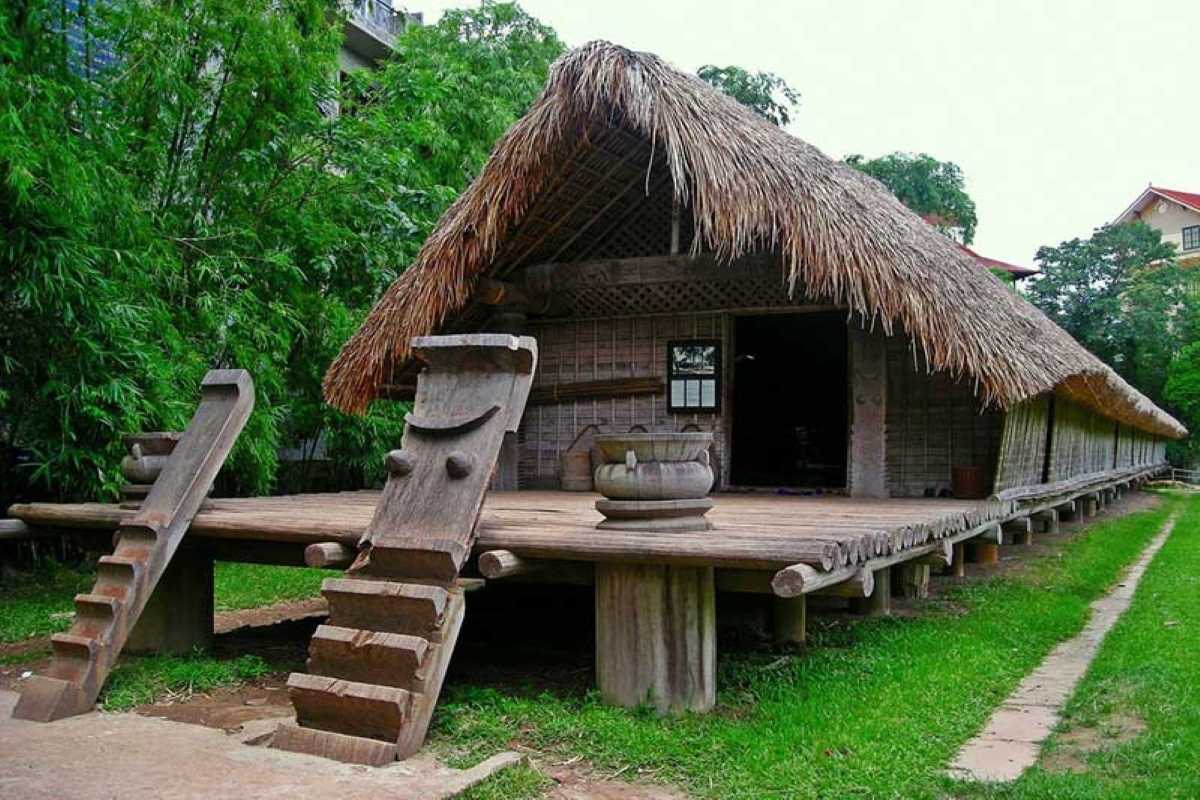 Vietnam Museum of Ethnology Hanoi ethnic village house replica Vietnam Museum of Ethnology Hanoi replica of ethnic village house surrounded by trees and wooden statues.