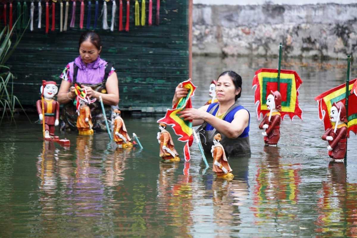 Vietnamese Puppeteers Preparing Water Puppets Vietnamese puppeteers adjusting colorful traditional water puppets in a pool during rehearsal