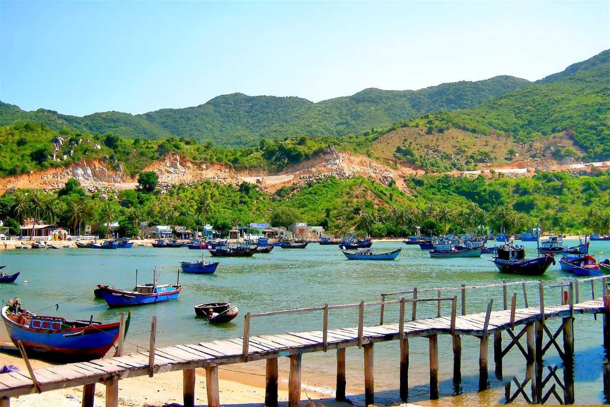 Vinh Hy Bay scenic coastal view with fishing boats Coastal view of Vinh Hy Bay showing vibrant fishing boats and lush green mountains in Ninh Thuan