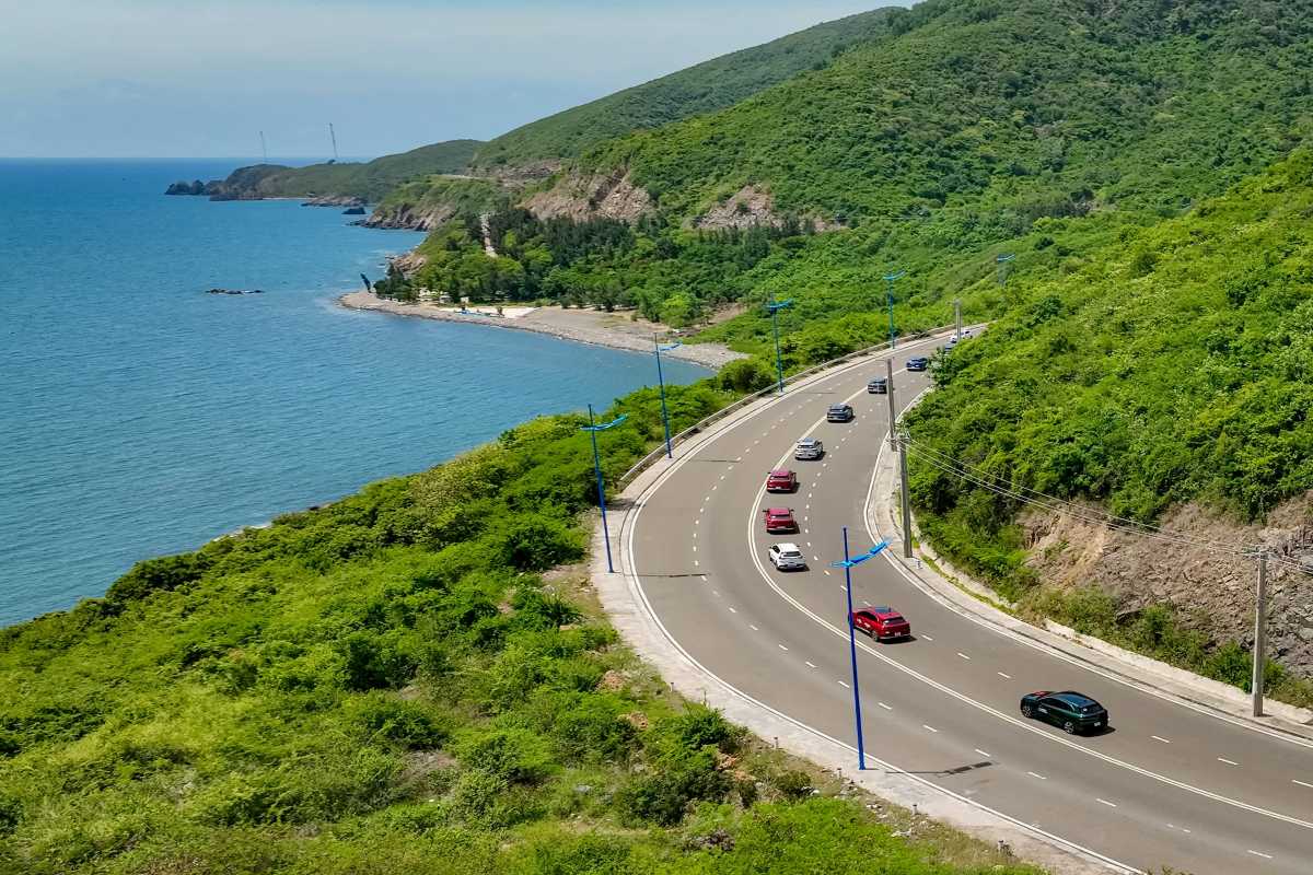Seaside Roadway Along Vĩnh Lương Cars driving on a coastal highway beside the sea, surrounded by greenery in the Vĩnh Lương area.