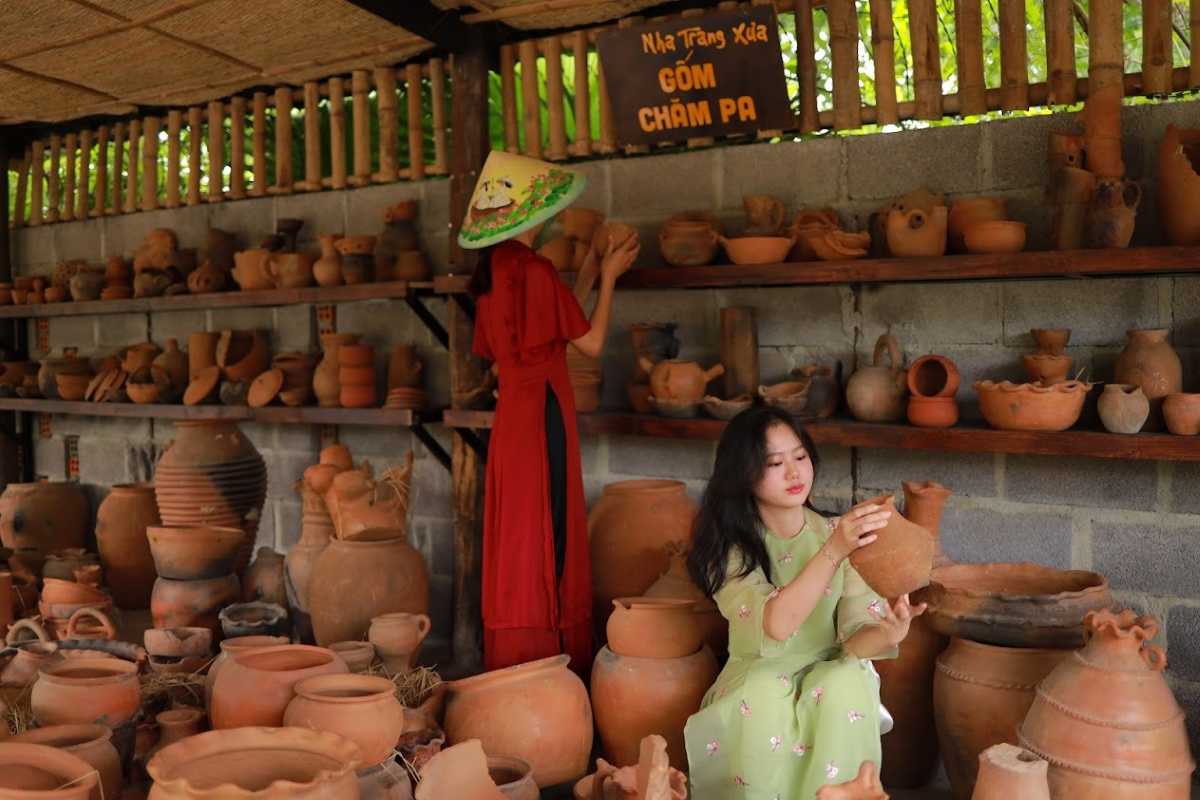 Visitors at Cham Pottery Village Two visitors observe and handle Cham-style terracotta pots at a handicraft village near Cai River in Nha Trang.