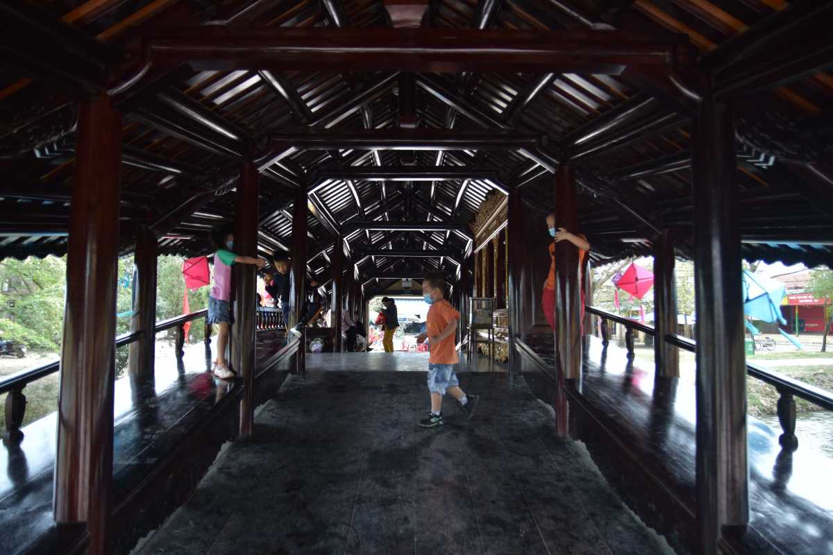 Busy Day at Thanh Toan Bridge with Visitors Visitors enjoying the peaceful environment on Thanh Toan Bridge surrounded by trees and water