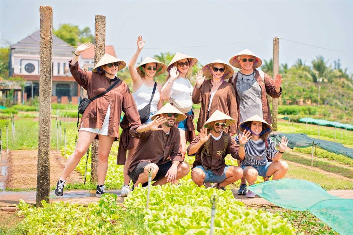 Visitors Enjoying Traditional Farming at Tra Que Vegetable Village Group of tourists wearing non la hats participating in traditional organic farming at Tra Que Vegetable Village