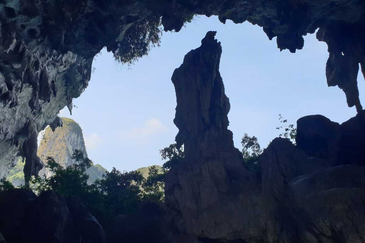 Visitors walking up the path to Drum Cave Halong Bay entrance Visitors climbing the stone and wooden path toward the entrance of Drum Cave Halong Bay surrounded by lush greenery.