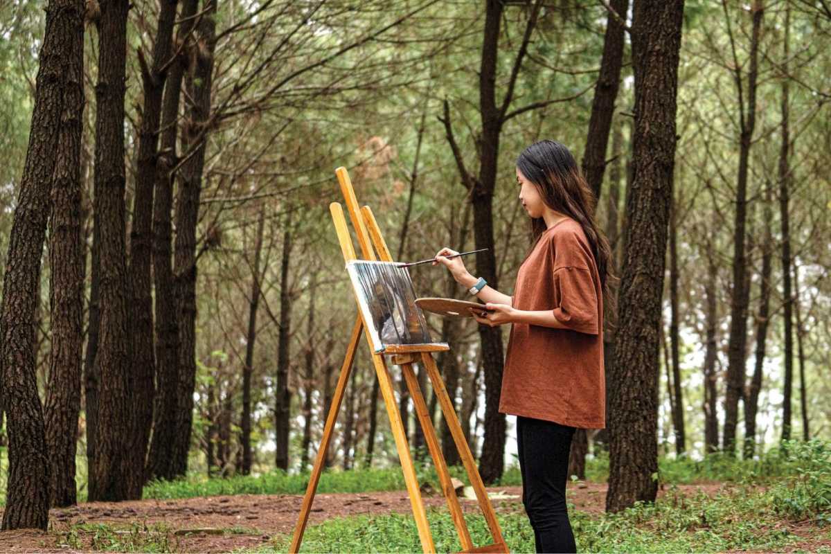 Vong Canh Hill Hue artist painting in pine forest An artist paints in the pine forest at Vong Canh Hill Hue, surrounded by trees and inspired by the tranquil, creative setting.