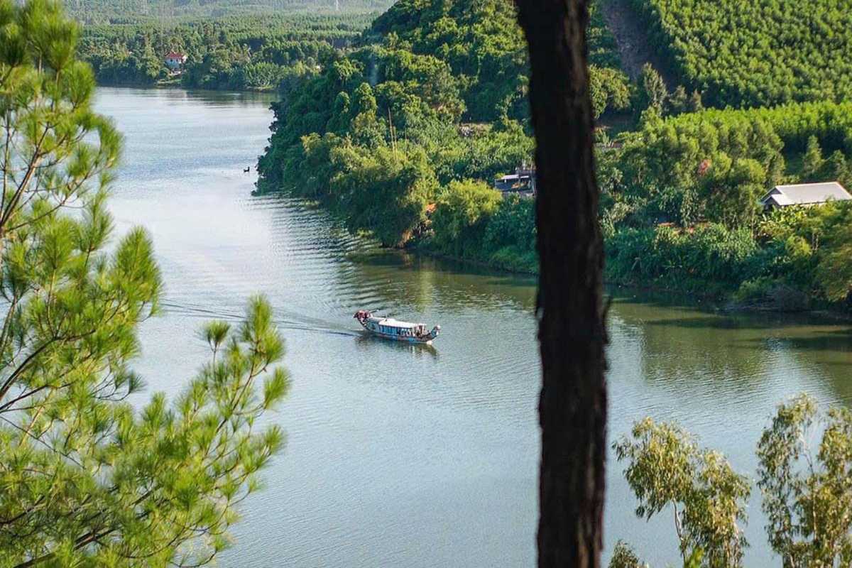 Vong Canh Hill Hue boat cruising Perfume River Vong Canh Hill Hue features a scenic overlook of the Perfume River with a traditional boat gliding past green riverside hills.