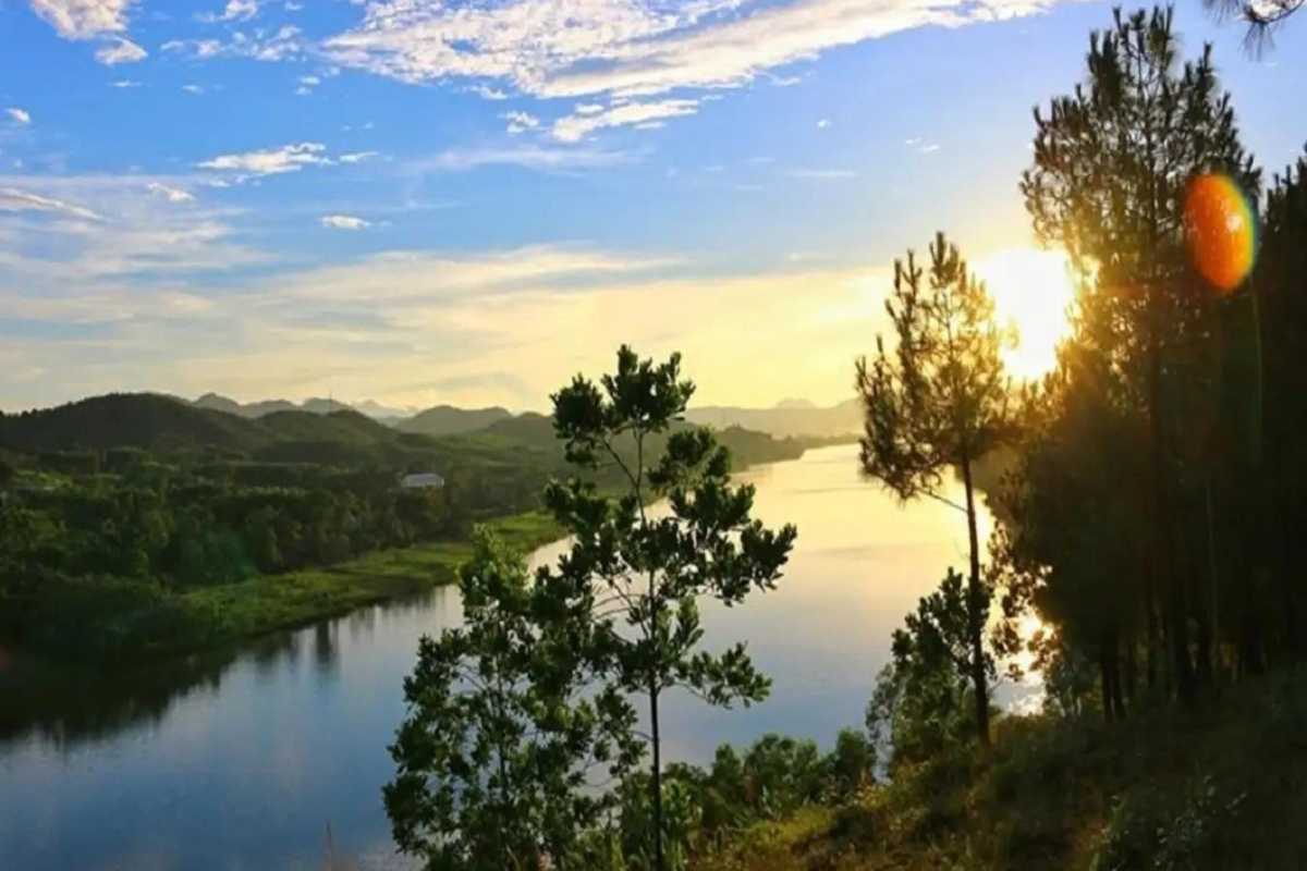 Vong Canh Hill Hue golden hour over forested hills The sun sets behind forested hills and the Perfume River at Vong Canh Hill Hue, bathing the landscape in a warm golden glow.