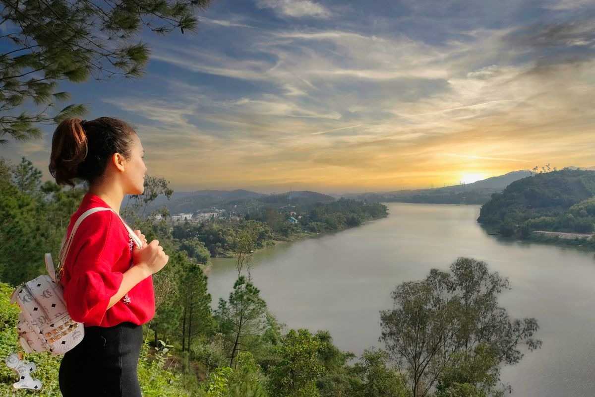 Vong Canh Hill Hue sunrise viewpoint overlooking river A traveler gazes out from Vong Canh Hill Hue at sunrise, with wide river views and the early light over mountains and forests.