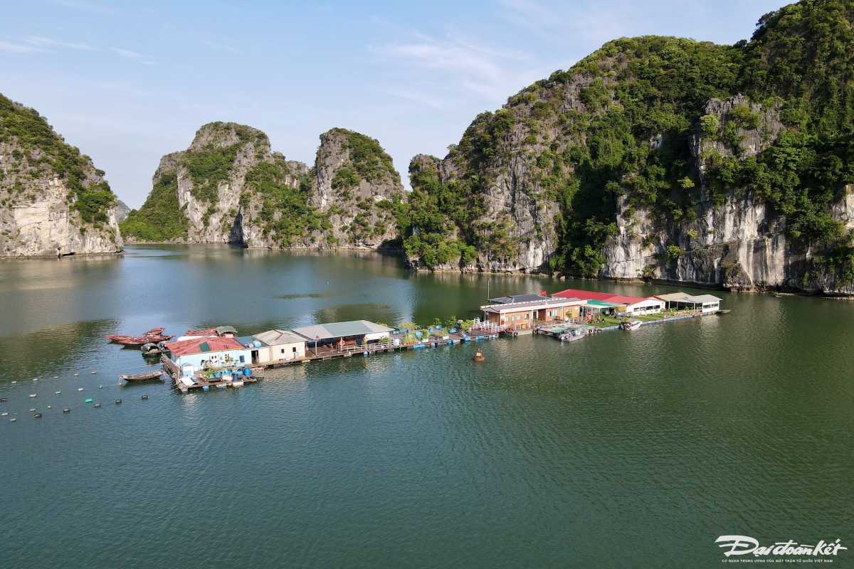 Vung Vieng Fishing Village boat trip experience Visitors on a small rowboat touring Vung Vieng Fishing Village with limestone cliffs in the background