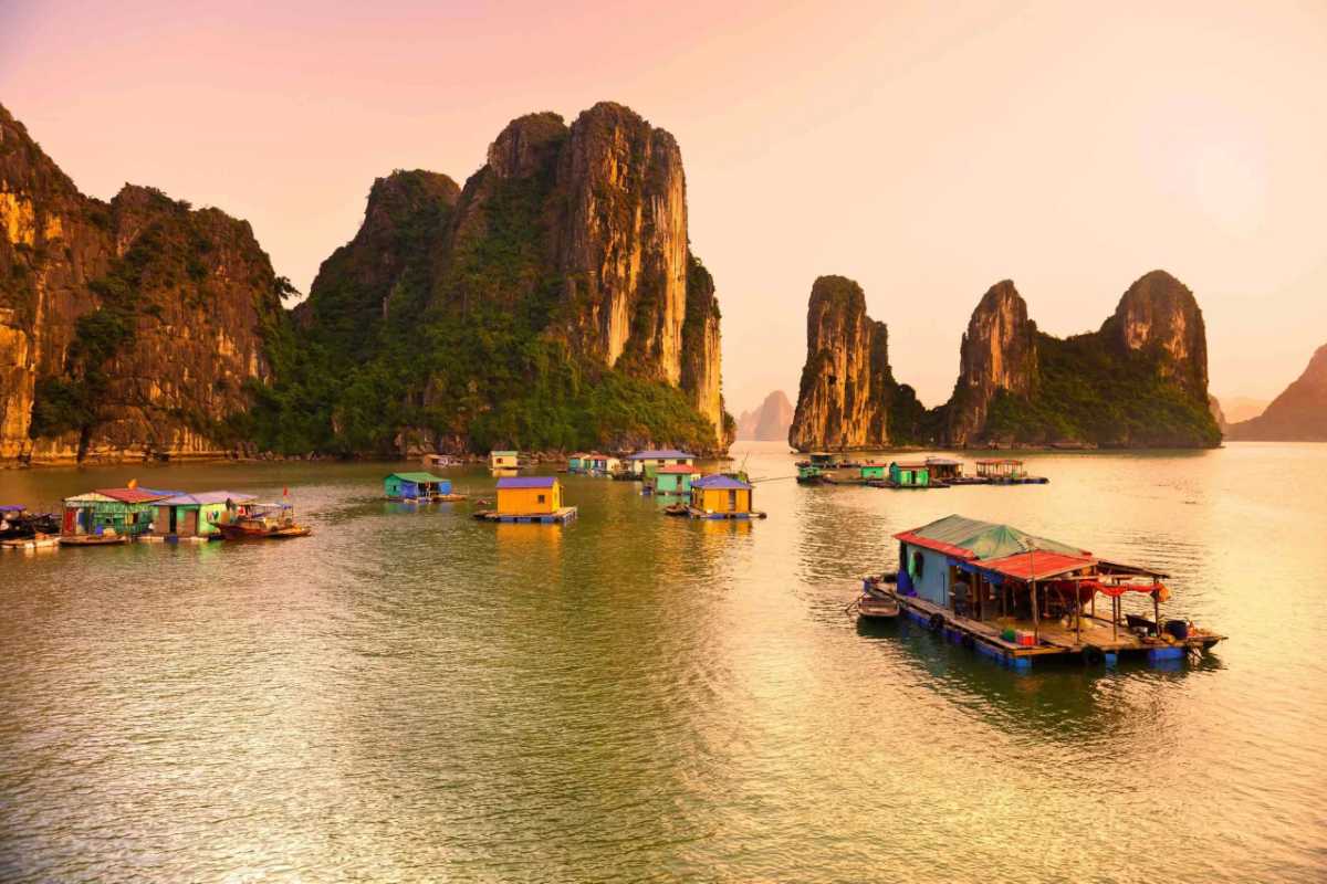 Vung Vieng Fishing Village colorful floating houses Colorful floating houses at Vung Vieng Fishing Village on Halong Bay with towering limestone islands in background