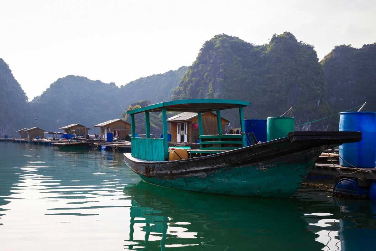 Vung Vieng Fishing Village floating community Floating community houses in Vung Vieng Fishing Village on Halong Bay with lush cliffs in the background
