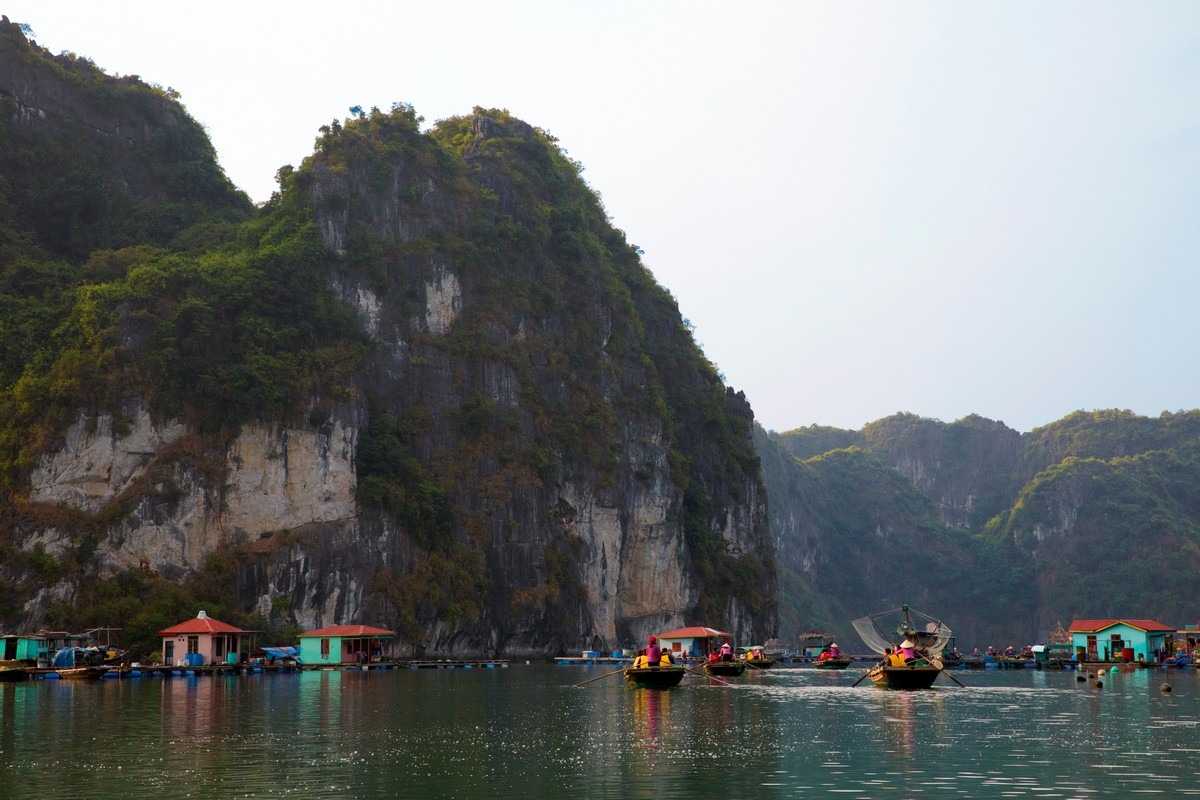 Vung Vieng Fishing Village traditional wooden fishing boats Traditional wooden fishing boats docked at Vung Vieng Fishing Village with limestone hills in the background