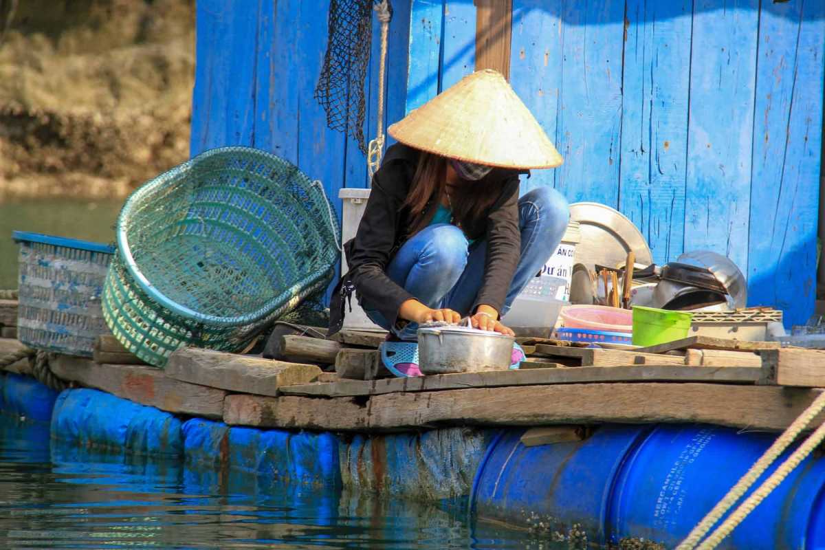 Vung Vieng Fishing Village waterfront washing activity Resident washing utensils on floating home deck at Vung Vieng Fishing Village on Halong Bay
