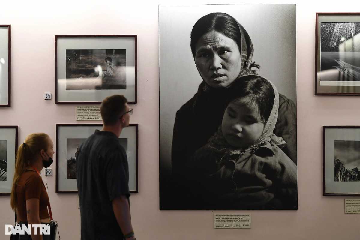 War Remnants Museum Visitors Viewing Historical Photos Visitors observing large historical photos of Vietnamese civilians during the war at the War Remnants Museum