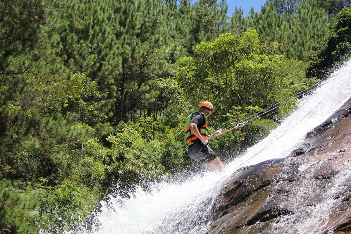 Waterfall Descent Adventure with Safety Gear at Datanla Individual descending waterfall using ropes and harness at Datanla Waterfalls, wearing life vest and helmet