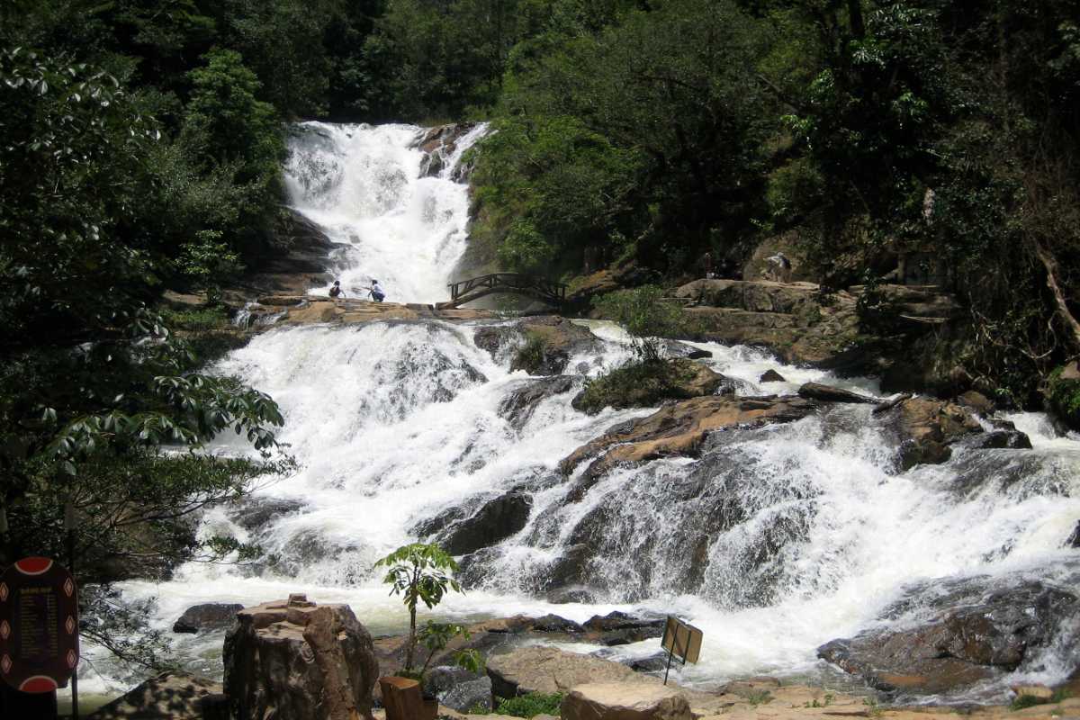 Exciting Waterfall Jump into Natural Pool at Datanla Adventurer jumping into the natural pool below Datanla Waterfalls, equipped with safety gear