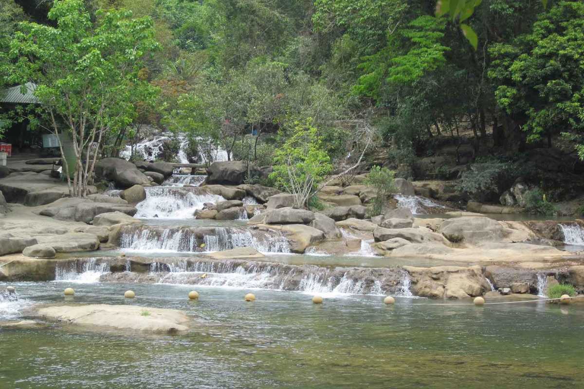 Natural cascade stream near Crocodile Farm Yang Bay with stone tiers and lush forest.