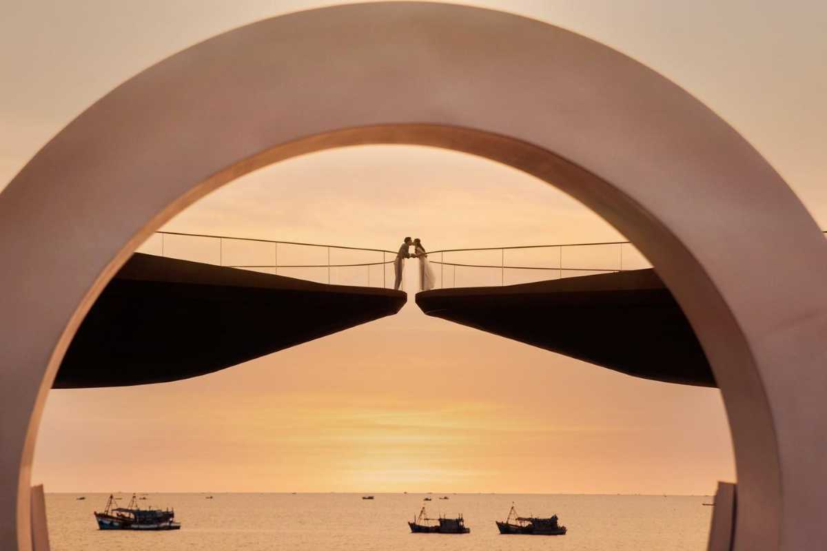 Kiss Bridge Phu Quoc Romantic Wedding Moment Bride and groom posing on Kiss Bridge Phu Quoc with sunset and sea background