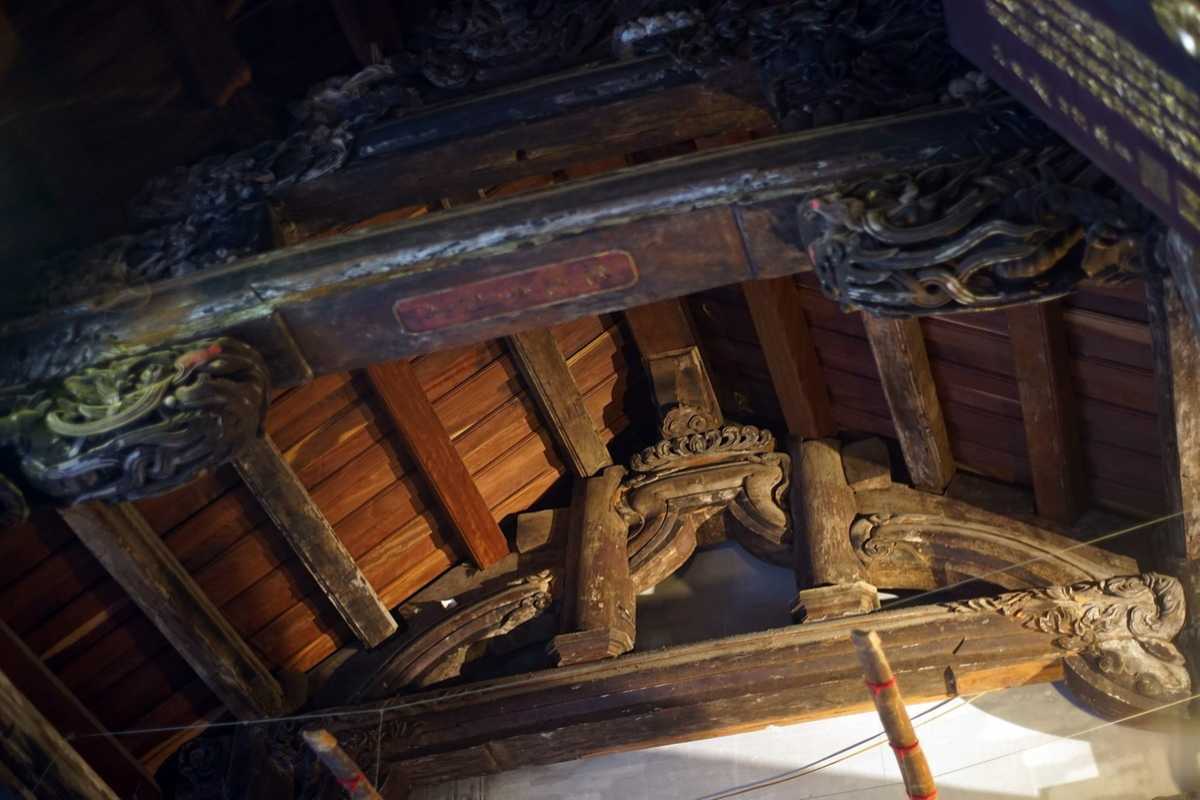 Intricate Wooden Roof Carvings at Quan Thanh Temple Detailed wooden carvings on the temple roof beams at Quan Thanh Temple