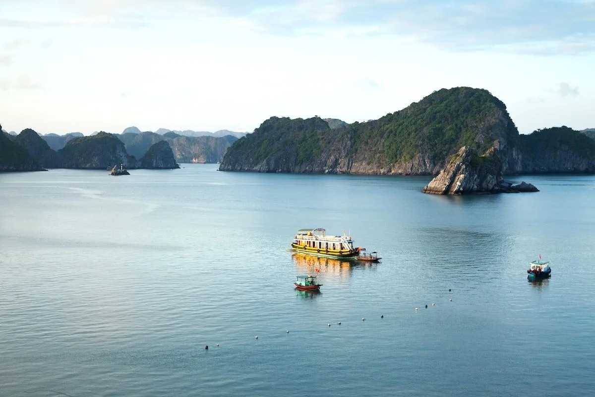 Xep Islet Halong Bay calm waters and boats Calm emerald waters around Xep Islet Halong Bay with boats and limestone islands