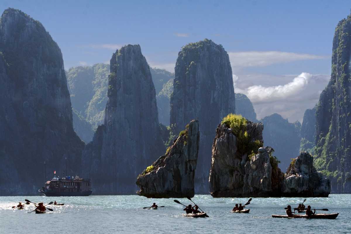 Xep Islet Halong Bay limestone cliffs and boats Traditional boats near limestone cliffs at Xep Islet Halong Bay on a sunny day