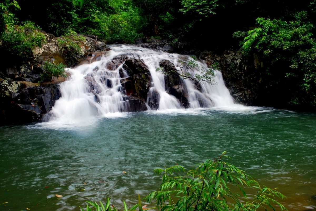 Tranquil Yang Bay Waterfall pool scene A quiet rock pool beneath cascading water at Yang Bay Waterfall surrounded by green vegetation