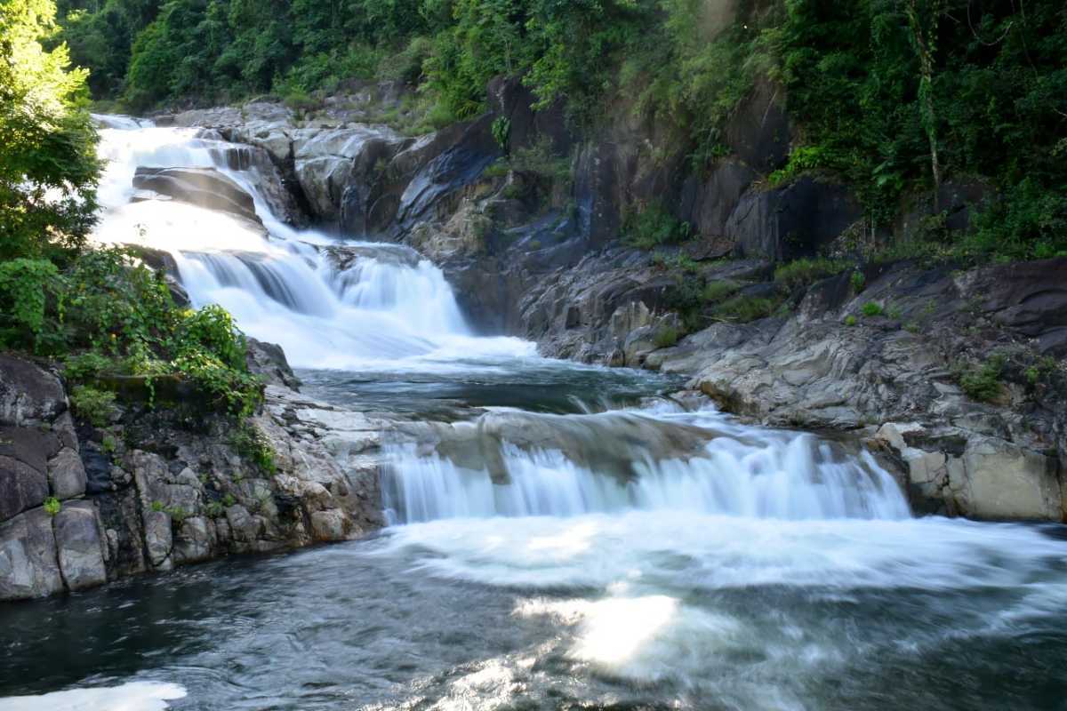 Peaceful cascade at Yang Bay Gentle water flowing over rocks at Yang Bay Waterfall with sunlight and forest shadows