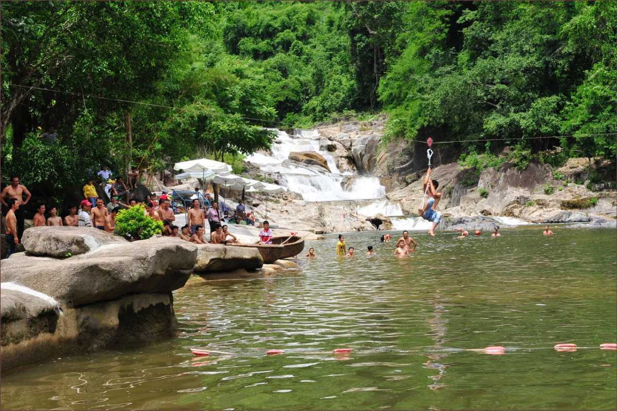 Yang Bay Waterfall swimming area Groups of tourists swimming and ziplining in the large open area at Yang Bay Waterfall