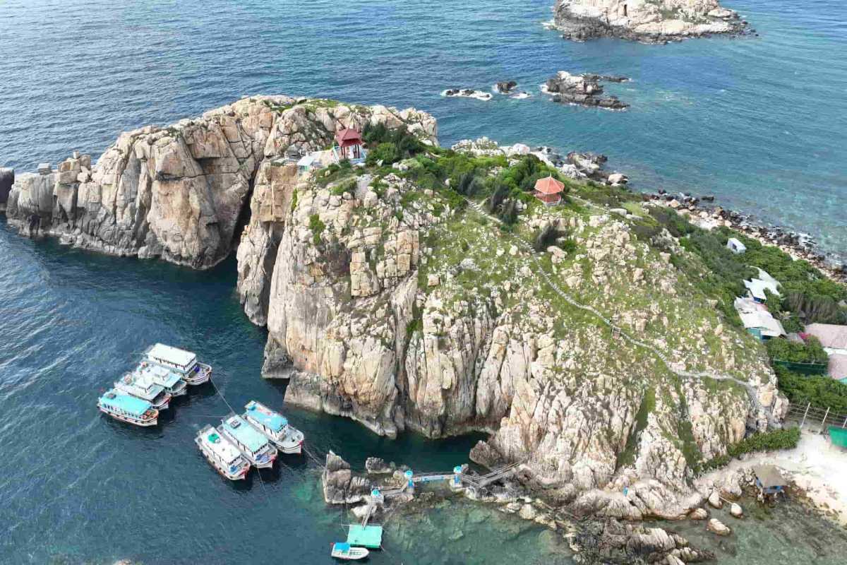 A stunning aerial view of Yen Island Nha Trang with clear blue waters, docked boats, and rocky cliffs.