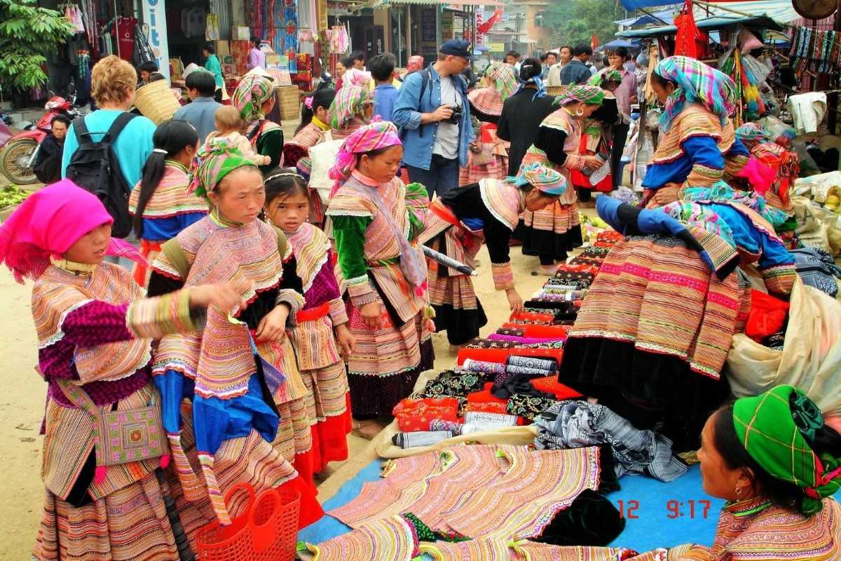 Young ethnic girls shopping at Coc Ly Market Ethnic girls in traditional dresses explore Coc Ly Market, surrounded by vivid fabric stalls and local vendors.