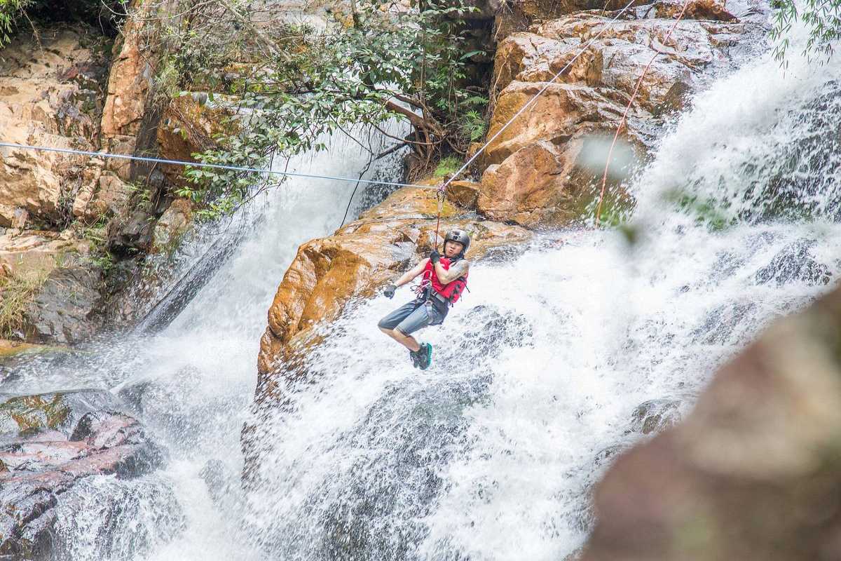 Ziplining Over Datanla Waterfalls’ Cascading Waters Adventurer soaring on zipline across flowing water at Datanla Waterfalls, with forest backdrop