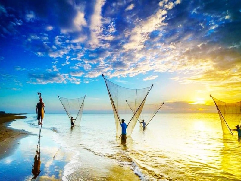 Fishermen at sunrise in Ba Dong Beach, Tra Vinh, casting nets into the sea.