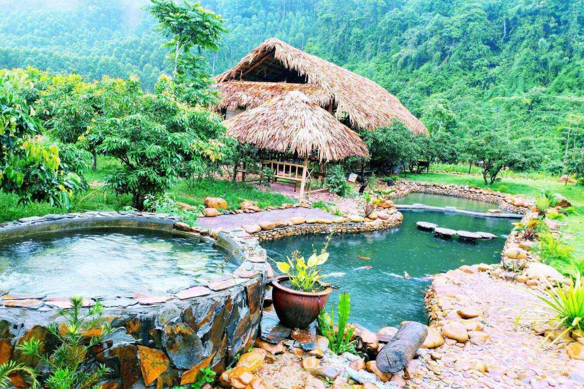 Bac Giang Travel Traditional Bamboo Cottage and Natural Pool Bac Giang Travel shows a traditional bamboo cottage beside a natural stone pool surrounded by lush greenery and mountains