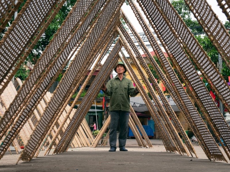 A man setting up bamboo mats in Tho Ha Village, Bac Giang, showcasing the local handicraft