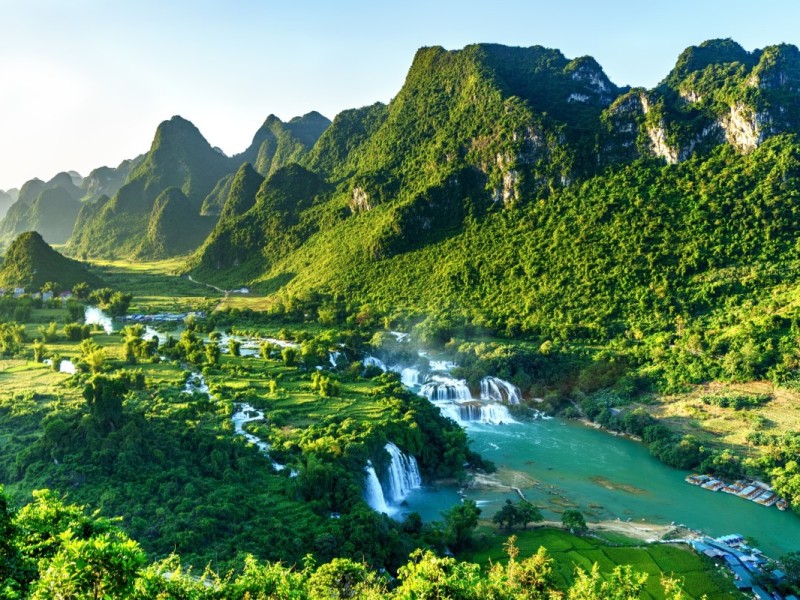 Ban Gioc Waterfall with the golden hues of sunrise lighting up the landscape in Cao Bang.