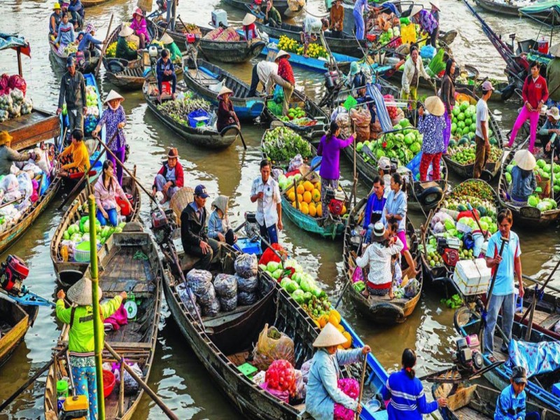 Boats filled with fresh produce and locals trading at Cai Be Floating Market in Tien Giang.