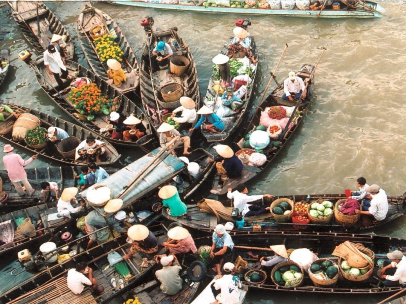 A vibrant image of Cai Be Floating Market in Tien Giang featuring boats filled with fruits, vegetables, and local products.