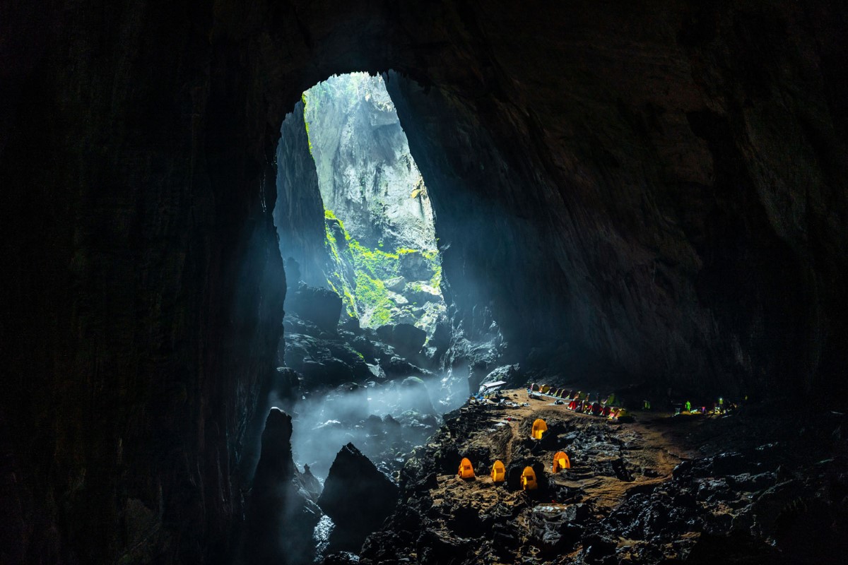 Camping adventure in Son Doong Cave with tents under massive cave entrance