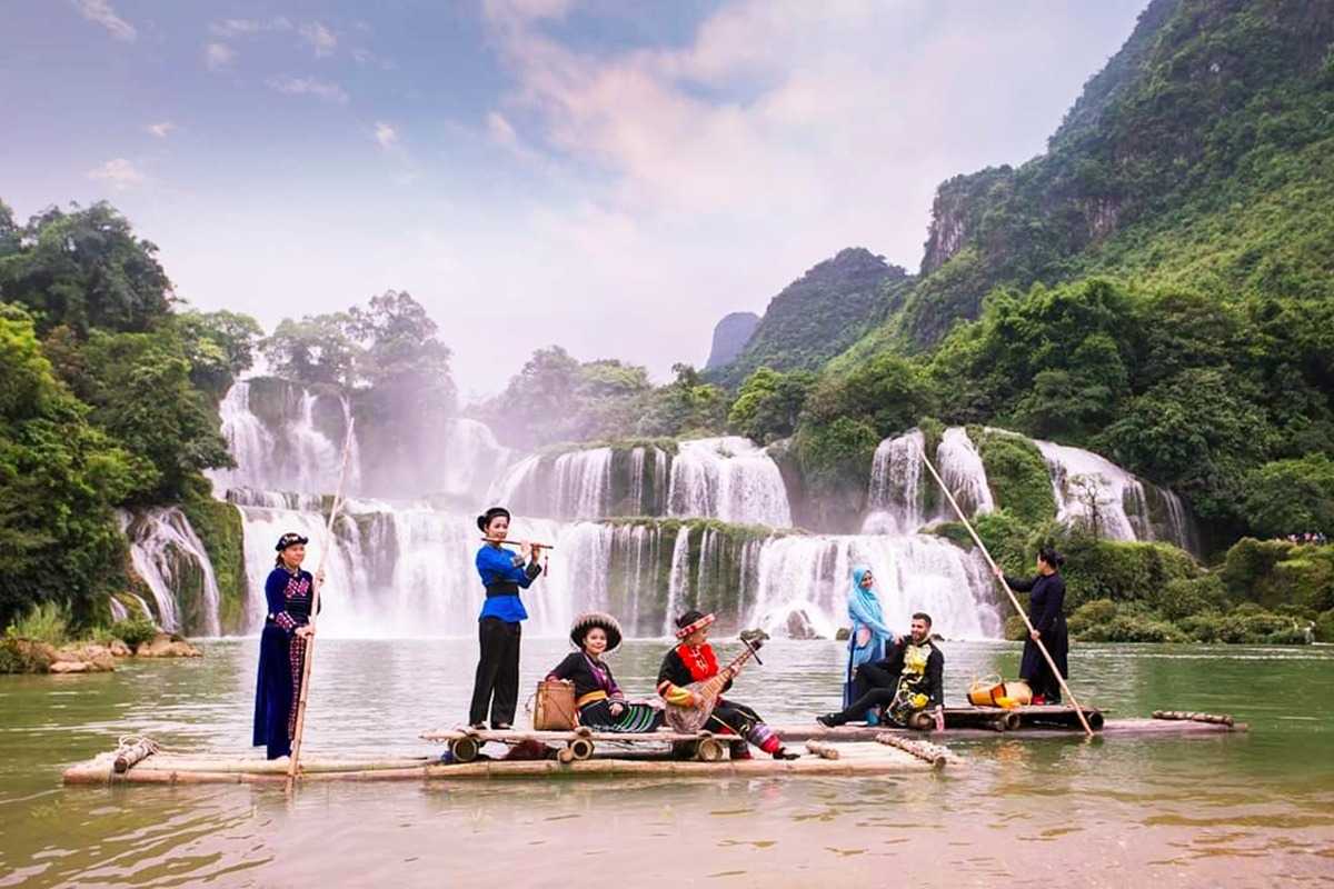 Cao Bang Travel Guide Ban Gioc Waterfall Bamboo Raft Experience Bamboo raft on Quay Son River with ethnic performers near Ban Gioc Waterfall in Cao Bang, showcasing cultural heritage and natural beauty