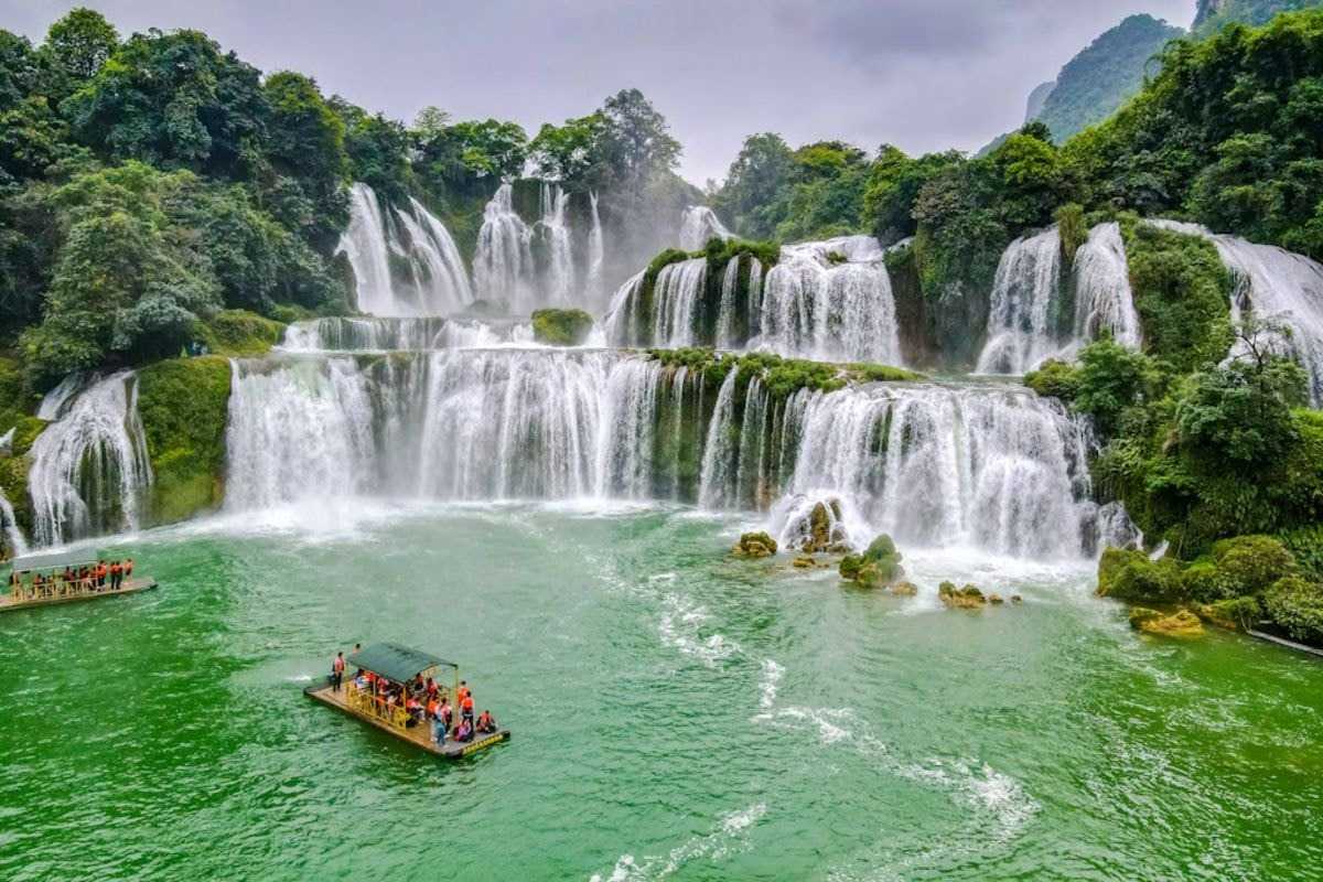 Cao Bang Travel Guide Ban Gioc Waterfall Tour Boat Tourist boat with visitors floating on emerald waters near Ban Gioc Waterfall in Cao Bang province