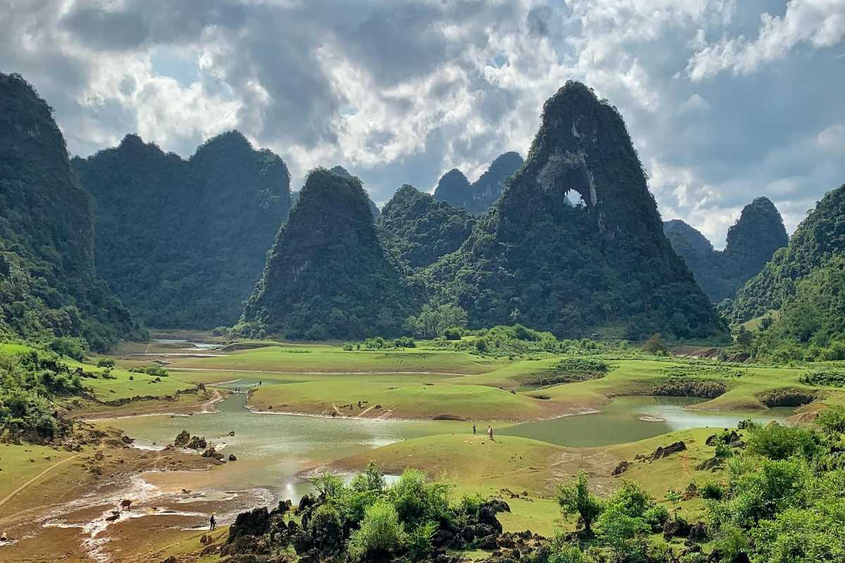 Cao Bang Travel Guide Buddhist Pagoda and Mountain View Traditional Buddhist pagoda with colorful flags overlooking green fields and limestone hills in Cao Bang