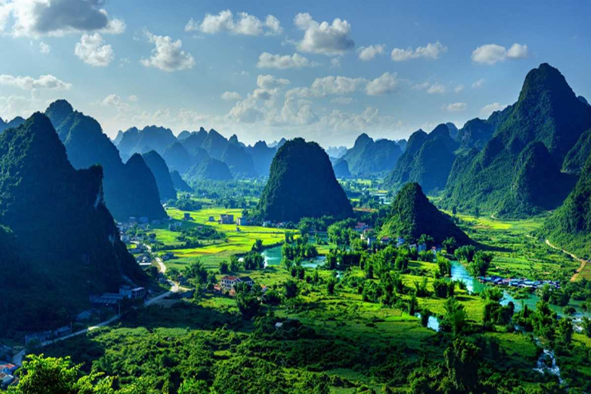 Cao Bang Travel Guide Karst Mountains and Valley View Vast landscape of Cao Bang’s karst mountains and green valleys under a bright blue sky, highlighting natural beauty