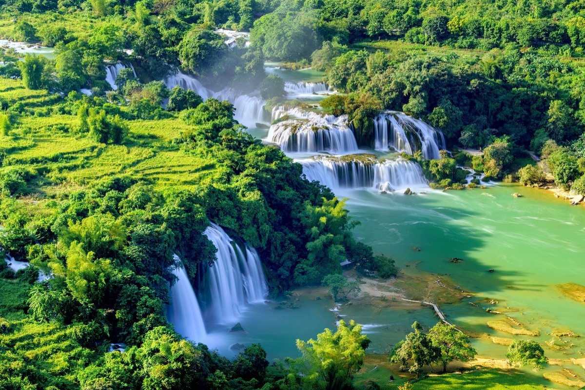 Cao Bang Travel Guide Road Through Mountains Scenic road cutting through verdant mountains and tea plantations in Cao Bang, inviting travelers to explore