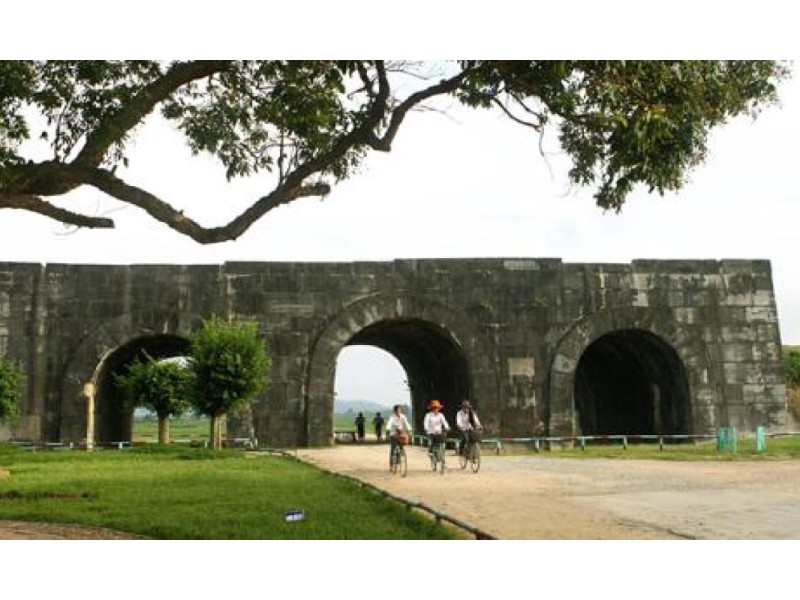 Cyclists near the Ho Citadel in Thanh Hoa under a tree-lined path