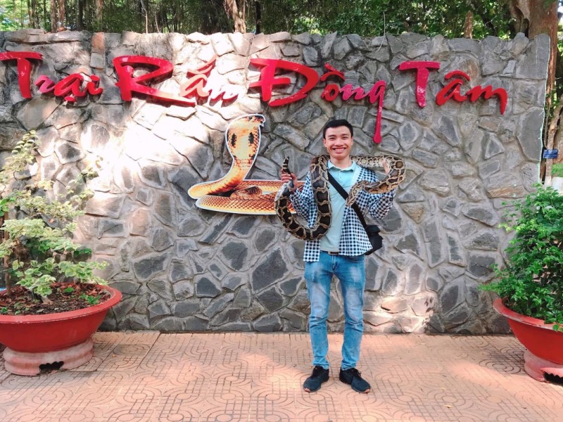 A visitor holding a large snake at Dong Tam Snake Farm, Tien Giang, Vietnam.