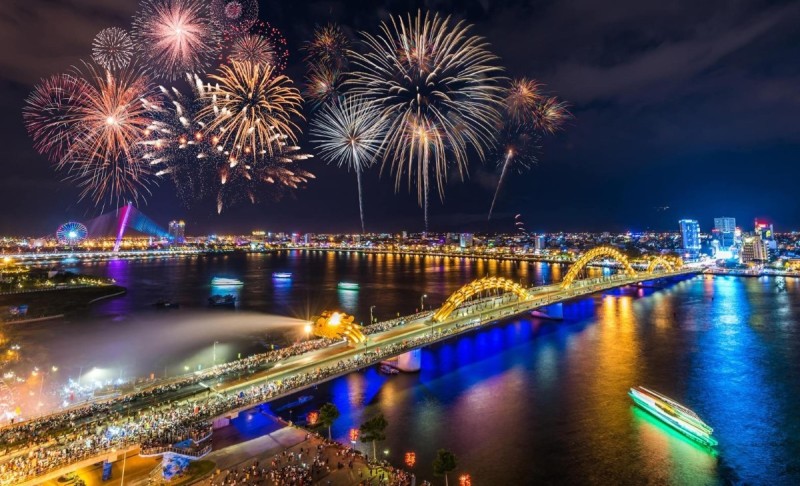 Fireworks over Dragon Bridge in Da Nang, Vietnam during a festival, with colorful lights illuminating the night sky.