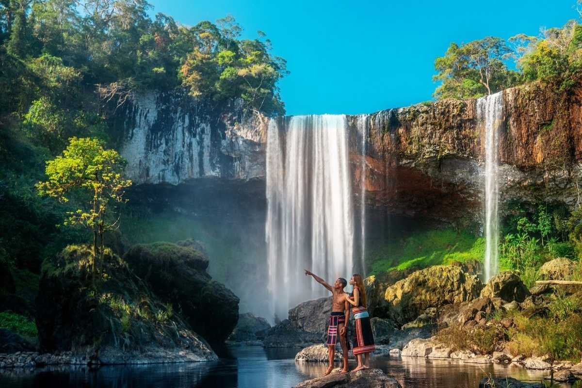 Gia Lai Waterfall with Rainbow Majestic waterfall cascading over cliffs with a visible rainbow and lush forest backdrop